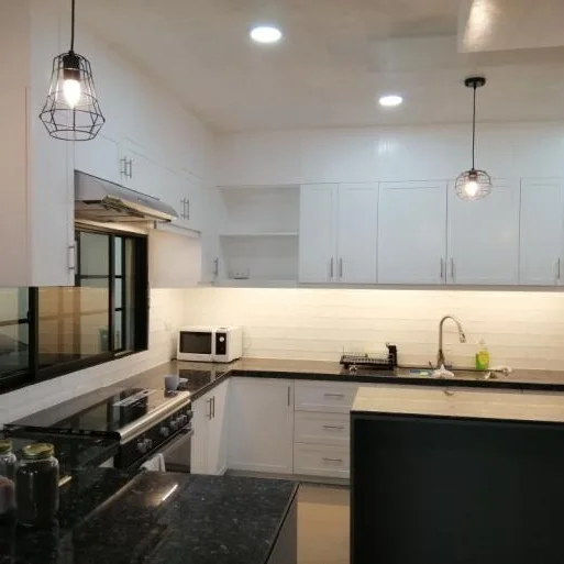 Kitchen with white overhead cabinets, dark granite counters, and hanging pendant lights